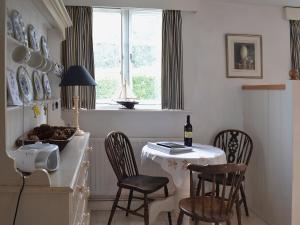 a kitchen with a table and chairs and a window at Apple Tree Cottage in West Wittering