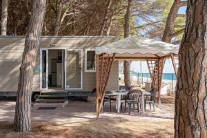 a caravan with a table and a gazebo at Camping&Village Le Cernie in Lotzorai