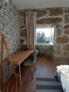 een houten bureau in een kamer met een raam bij A CASA COM 2 PEREIRAS in Terras de Bouro