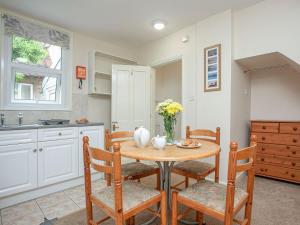 une cuisine avec une table et des chaises et une cuisine avec des placards blancs dans l'établissement Apartment Five - Uk39841, à Paignton