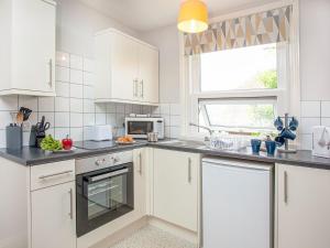 a white kitchen with white cabinets and a window at Apartment Eleven - Uk39864 in Paignton