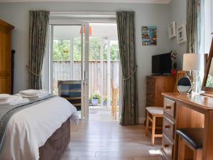 a bedroom with a bed and a sliding glass door at Ashlea At Amberley in Sidmouth