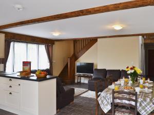 cocina y sala de estar con mesa y sofá en Llaethdy-milkhouse, en Talgarth