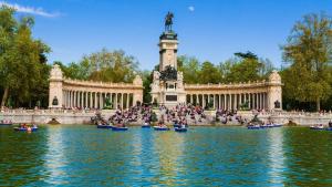 Un gruppo di persone in canoa nell'acqua di fronte a una statua. di HABITACIÓN en el centro de Madrid a Madrid