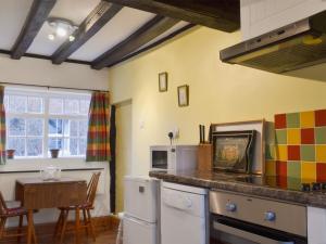 a kitchen with a counter top and a table with a table at Swiss Cottage - E5375 in Alrewas