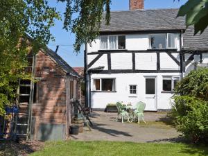 a house with two chairs and a table in the yard at Swiss Cottage - E5375 in Alrewas