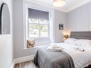 een witte slaapkamer met een kat in een raam bij Well Strand in Rothbury