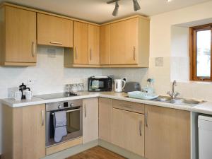 a kitchen with wooden cabinets and a microwave at Quarry Cottage in Penrith