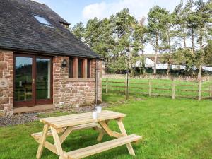 a wooden picnic table in front of a brick house at Quarry Cottage in Penrith