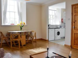 a living room with a table and a kitchen at Sunset Song in Arbuthnott