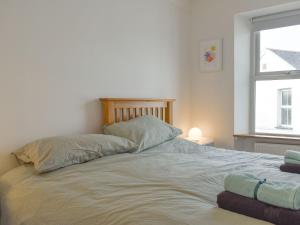 een wit bed met 2 kussens en een raam bij Berkeley Cottage in Ilfracombe
