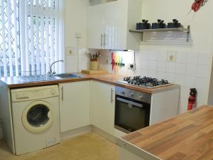 a kitchen with a stove and a washing machine at The Garden Flat in Torquay