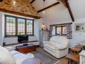 uma sala de estar com dois sofás brancos e uma televisão em Stable Cottage em Uley