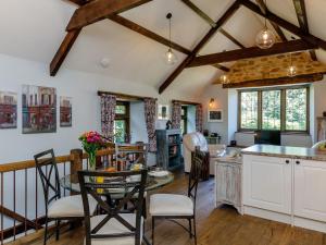 Stable Cottage في Uley: مطبخ مع دواليب بيضاء وطاولة مع كراسي