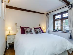 a bedroom with a white bed and a window at Stable Cottage in Uley