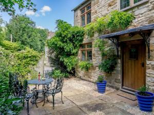 a patio with a table and chairs in front of a building at Stable Cottage in Uley