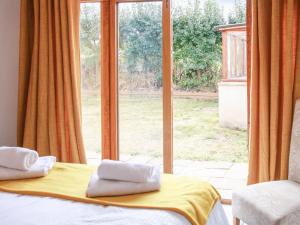 a bedroom with a bed and a large window at Haycart Barn in Long Stratton