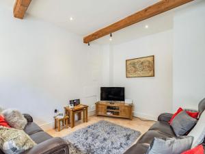 a living room with a couch and a tv at Shire Cottage - Uk37451 in Pateley Bridge