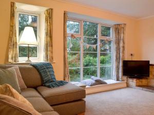 a living room with a couch and two windows at The Mill Cottage in Ault Hucknall