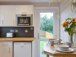 a kitchen with a table with a vase of flowers at Blackmill Cottages No 2 in Taynuilt