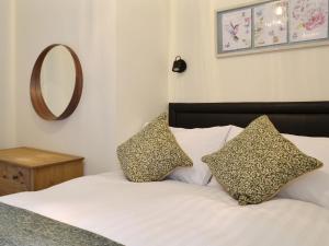 a bedroom with a bed with two pillows and a mirror at Blackmill Cottages No 2 in Taynuilt