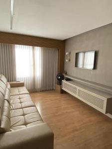 a living room with a couch and a television at ENCANTADOR , MODERNO E CONFORTÁVEL !!! in Belo Horizonte