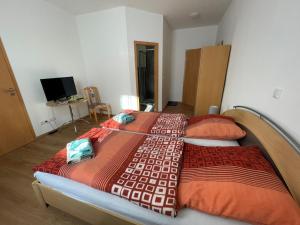 a bedroom with two beds with red and orange blankets at Hotel Zur Henne in Schmiedefeld am Rennsteig