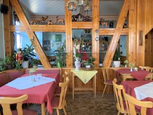 a restaurant with two tables with red tablecloths at Hotel Zur Henne in Schmiedefeld am Rennsteig