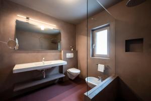 a bathroom with a sink and a toilet and a mirror at Paramount Alma Suites Sexten in Sesto +100 photos