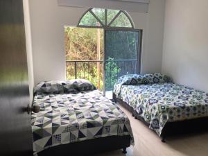 1 dormitorio con 2 camas y ventana en Casa Flandes Tolima, en Flandes