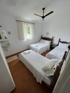 a bedroom with two beds and a ceiling fan at Villa Interlagos de Minas in Guapé