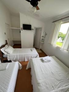 a room with three beds and a television in it at Villa Interlagos de Minas in Guapé