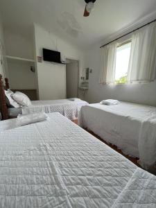 a bedroom with two beds and a window with a television at Villa Interlagos de Minas in Guapé