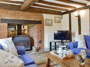 a living room with a blue couch and a fireplace at Meadow Cottage in Chediston