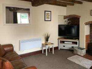 a living room with a couch and a television at Repton Cottage - 25348 in Findern