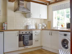 una cucina con armadi bianchi e una lavatrice/asciugatrice di Repton Cottage - 25348 a Findern