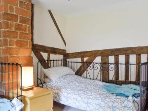 a bedroom with a bed and a brick wall at Meadow Cottage in Chediston