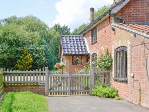 a wooden fence in front of a brick house at Meadow Cottage in Chediston