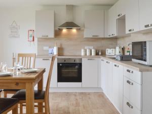 a kitchen with white cabinets and a wooden table at Rockworks Chalets No,6 - Uk7045 in Saint Marys