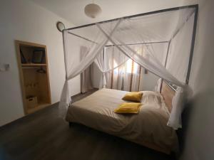 een slaapkamer met een hemelbed met gele kussens bij Villa Idaka in Rufisque