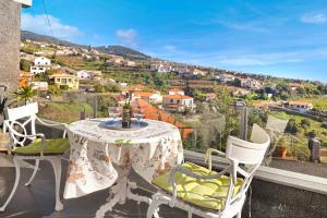 a table and chairs on a balcony with a view at Vila Morning Sun in Estreito da Calheta