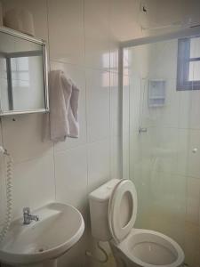 a white bathroom with a toilet and a sink at Pousada Acqua Infinity PISCINA CLIMATIZADA PÉ NA AREIA in Bertioga