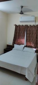 1 dormitorio con 1 cama blanca grande con cortinas en HOTEL RAJMANDIR, en Santiniketan
