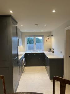 eine Küche mit schwarzen Schränken und einem Fenster in der Unterkunft Newly built house with elegant touches... in Todenham