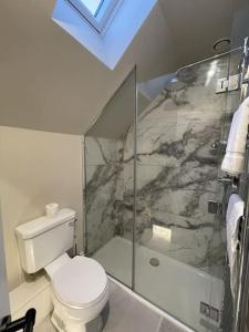 a bathroom with a toilet and a glass shower at Newly built house with elegant touches... in Todenham