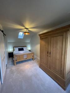 Schlafzimmer mit einem Bett und einem Holzschrank in der Unterkunft Newly built house with elegant touches... in Todenham