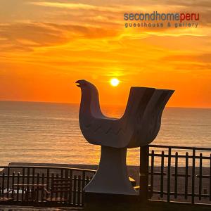 uma estátua de um pássaro na praia ao pôr do sol em Second Home Peru em Lima