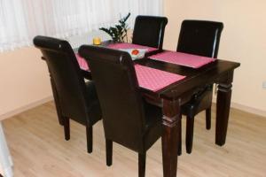 una mesa de madera con sillas negras y una mesa con servilletas rosas en FeWo ab 3 Übernachtungen, en Dresden