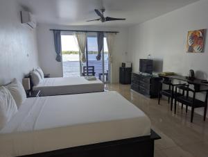 1 dormitorio con 2 camas, escritorio y TV en Inn The Town, en Port Antonio