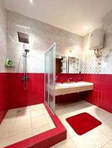a red bathroom with a shower and a sink at The Dzorwulu Castle - A Villa with private rooms in Accra